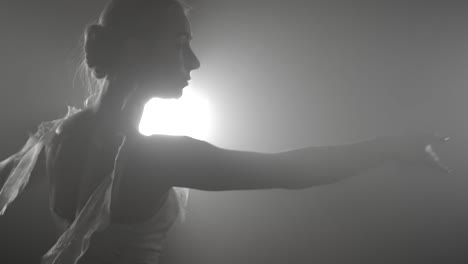 Professional-ballerina-dancing-ballet-in-spotlights-on-big-stage.-Beautiful-caucasian-young-girl-wearing-white-tutu-dress.-Black-white-vintage-retro-effect-tonned.-Slow-motion