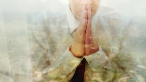 Reflection-of-a-businessman-praying-against-a-window