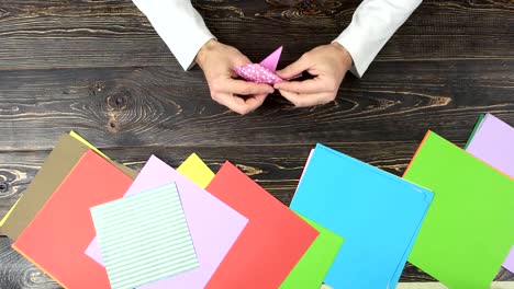 Man-folding-origami-from-pink-paper.