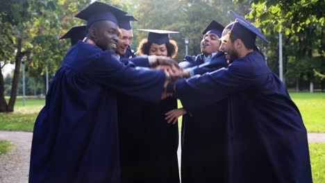 happy-students-in-mortar-boards-with-hands-on-top