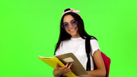 Glückliche-junge-Schülerin-posiert-mit-ihren-Büchern-und-Rucksack