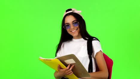 Happy-young-female-student-posing-with-her-books-and-backpack