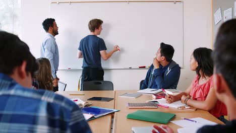 Hombre-alto-escuela-pupila-escritura-en-pizarra-en-clase-de-matemáticas