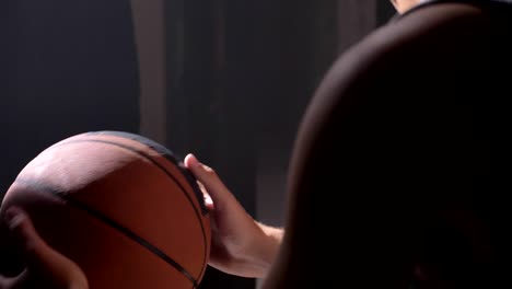 Basketball-Spieler-sitzen-und-spielen-mit-Ball,-warten-auf-Spielplatz-in-nebligen-Dunkelkammer-gehen