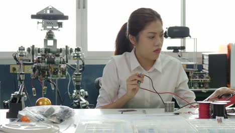 Ingeniero-en-electrónica-mujer-mide-la-señal-en-el-circuito-eléctrico-en-su-taller.-Estudiante-chica-estudiando-electrónica-en-aula.