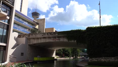 San-Antonio-River-Walk-Boote-und-Gebäude-mit-Turm-im-Hintergrund