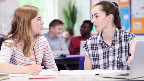 Lehrer-mit-zwei-weiblichen-Schülerinnen-und-Schüler-arbeiten-am-Laptop-im-Klassenzimmer