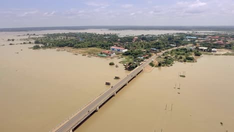 drone-:-flying-over-a-concrete-bridge-running-across-the-flooded-river-in-rural-area