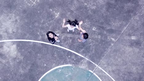 Aerial-view-of-girls-enjoy-playing-at-basketball-yard-in-evening