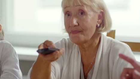 Senior-Woman-Watching-TV-and-Talking-with-Family-at-Dinner