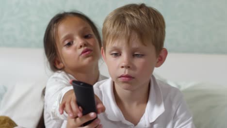 Pequeño-niño-y-una-niña-viendo-la-TV-en-la-cama