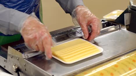 Saleswoman-slicing-cheese-in-a-supermarket-and-wrapping-it-in-cling-film.