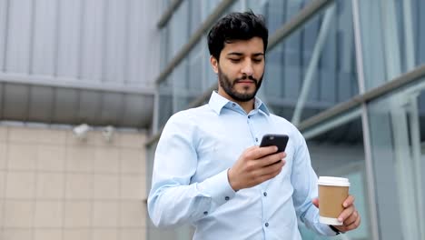 Hombre-de-negocios-guapo-con-teléfono-y-café-en-la-calle