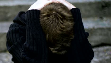 Depressed-schoolboy-hiding-face-under-hoodie,-victim-of-bulling,-homelessness