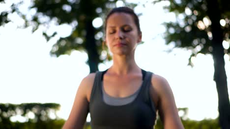 Schöne-schlanke-Frau-im-Lotussitz-praktizieren-Yoga-im-Park.