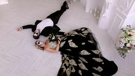 A-couple-with-makeup-on-their-face-lie-on-the-floor-in-a-vintage-room.-Halloween