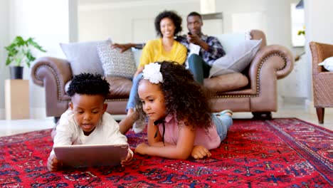 Vista-frontal-de-niños-negros-lindos-con-tableta-digital-en-sala-de-estar-en-casa-cómodo-4k