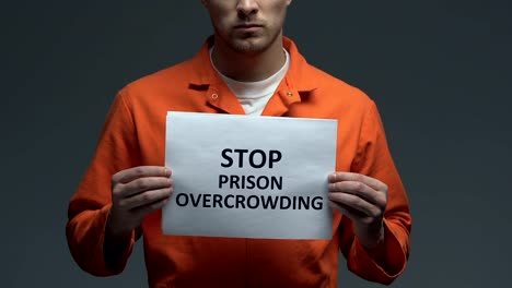 Stop-prison-overcrowding-phrase-on-cardboard-in-hands-of-Caucasian-prisoner