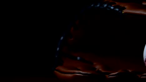 Werfen-Sie-einen-Baseball-mit-einem-Baseballhandschuh,-in-ein-dunkles-Licht-gelegt