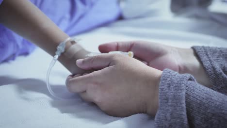 Mother-holding-hand-of-his-son-sick-bed-in-the-hospital.-Touch-the-hand-Slow-motion.-care-encouragement