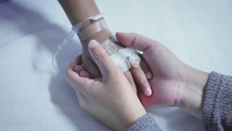 Mother-holding-hand-of-his-son-sick-bed-in-the-hospital.-Touch-the-hand-Slow-motion.-care-encouragement