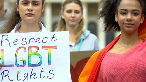 Pareja-femenina-tomando-las-manos-sosteniendo-cartel-de-derechos-LGBT,-apoyo-para-el-matrimonio-gay