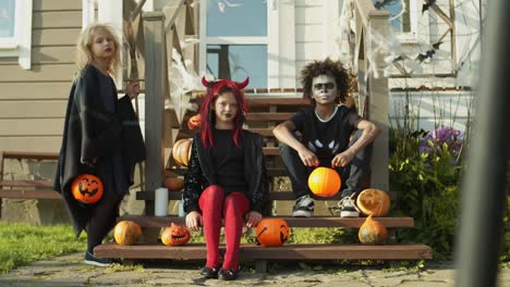 Tres-niños-con-trajes-de-Halloween-sentados-en-el-porche