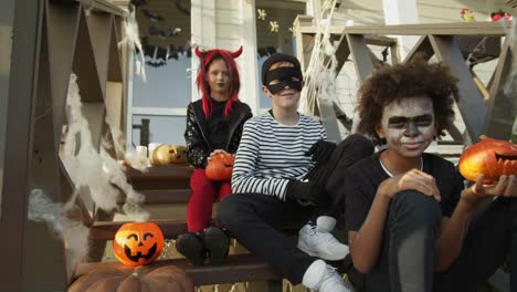 Drei-Teenager-tragen-Halloween-Kostüme-sitzen-auf-Veranda