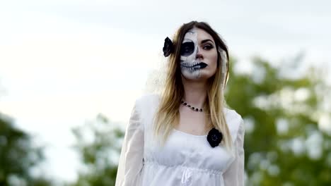 The-young-woman-with-spooky-make-up-for-Halloween-in-a-white-bride-dress.-4K