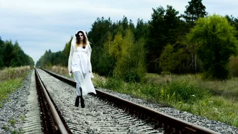 A-woman-with-make-up-of-dead-bride-for-Halloween-in-wedding-gown-on-the-rails.-4K