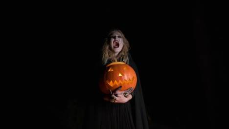 Halloween-Image-.Young-Witch-In-Black-Clothes-Holds-Pumpkin-In-Her-Hands.