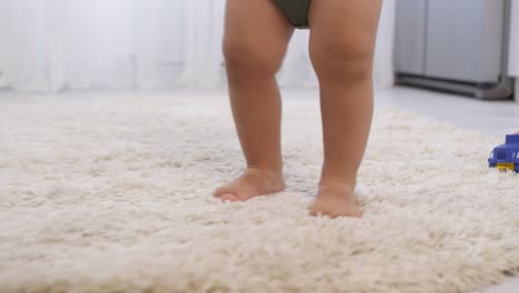 Legs-of-Barefoot-Toddler-Walking-on-Carpet-and-Sibling-Sitting-beside