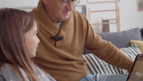 Granddad-and-Granddaughter-Playing-Game-on-Laptop