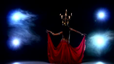 Attractive-belly-dancer-girl-continue-dancing-with-candles-on-her-head,-black,-smoke