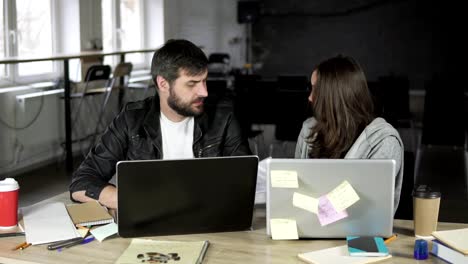 Young-office-workers-arguing-in-front-of-their-laptops.-Woman-showing-papers-being-very-angry.-Slowmotion