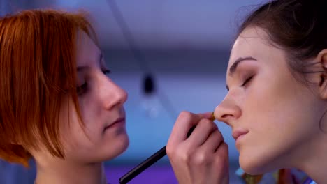 Concept-of-beauty-and-fashion.-Professional-makeup-artist-applying-cosmetics-on-model-face.-Zoom-out