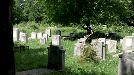 Mujer-joven-vestida-con-ropa-de-funeral-en-el-cementerio-entre-las-tumbas