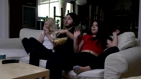 Roommates-eating-popcorn-at-home-get-scared-while-watching-horror-movie