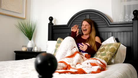 Cute-attractive-millennial-woman-watches-a-funny-movie-in-her-bedroom-while-eating-popcorn-ALT