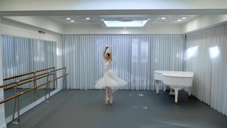 Ballerina-in-long-ballet-tutu-dances-in-studio-with-white-grand-piano