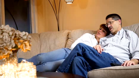 Middle-aged-couple-on-couch-watching-some-irritating-political-news-story-ALT