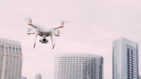 Quadcopter-drone-with-camera-on-gimbal-flying-in-the-city-sky,-shot-in-slow-motion