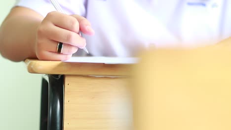 Los-alumnos-con-goma-de-borrar-lápiz-teniendo-exámenes,-sala-de-examen,-escribir-respuesta-óptica-forma-en-el-aula-de-secundaria,-ver-de-tener-prueba-de-clase-en-las-filas-de-asiento,-concepto-de-alfabetización-de-educación.