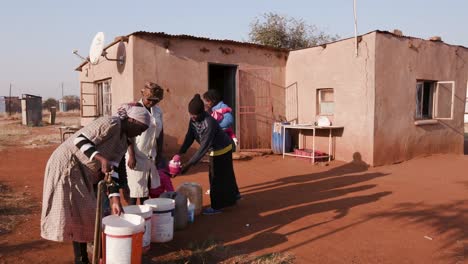 Afrikanische-Frau-und-Kinder-richten,-Wasser-in-Plastikbehältern-aufgrund-der-schweren-Dürre-in-Südafrika-zu-sammeln