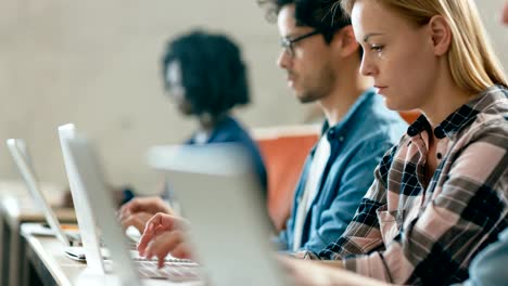 Zeile-der-Multi-ethnischen-Studenten-arbeiten-auf-den-Laptops-beim-hören-einen-Vortrag-im-modernen-Unterricht.-Helle-Jugendliche-Studie-an-der-Universität.