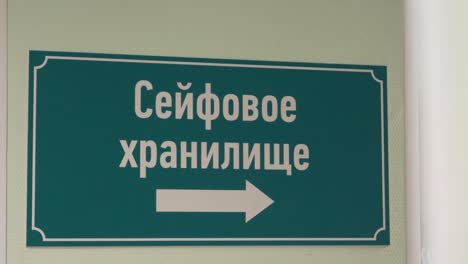 Green-plastic-sign-on-wall-with-russian-text-sais-safe-depository