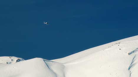 Heliski-helicóptero-vuela-sobre-el-trasfondo-de-las-montañas-nevadas