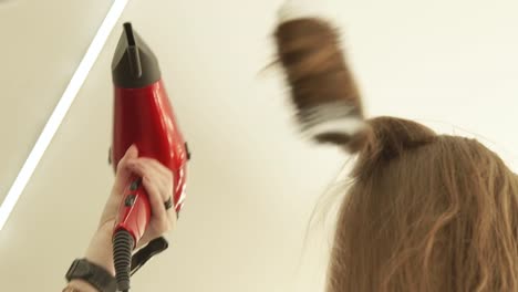 Hairdresser-hairstyling-long-hair-with-brush-and-dryer-after-hairdressing.-Close-up-haircutter-drying-long-hair-with-dryer-and-hairbrush.-Finish-hairdressing-in-beauty-salon