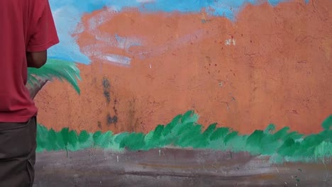 Mural-painter-paints-a-garden-background-image-in-color-on-the-school-wall.-time-lapse