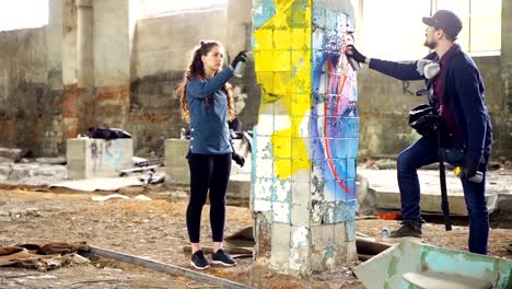 Slow-motion-of-creative-graffiti-painters-partners-decorating-abandoned-house-with-beautiful-images-using-bright-aerosol-paint.-Teamwork,-young-people-and-art-concept.